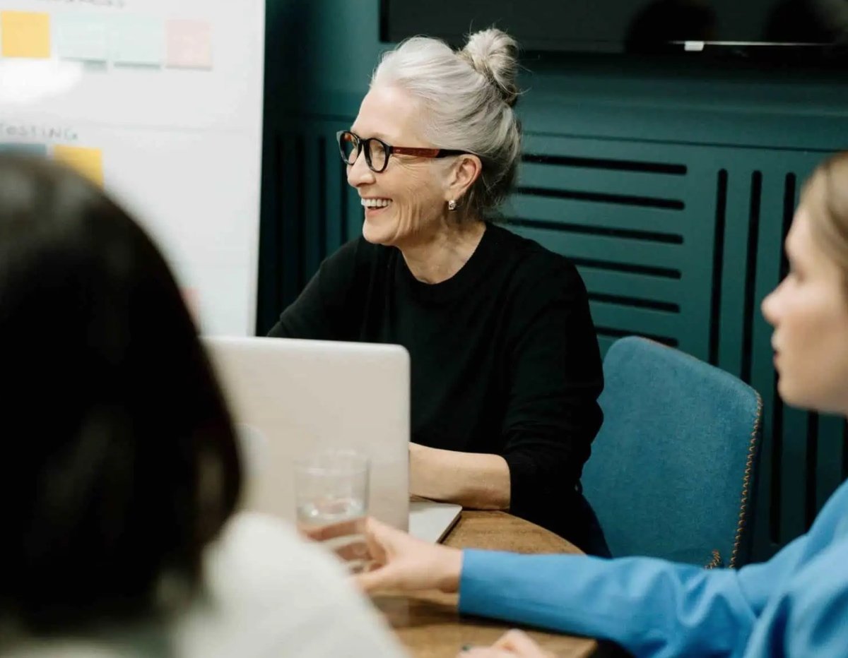 smiling woman sitting at a laptop - ai in finance myths blog feature